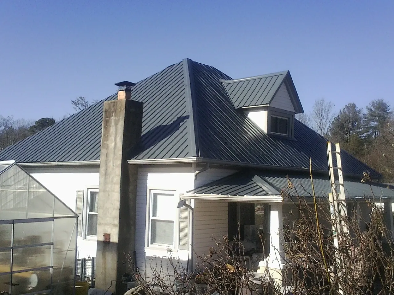 Dark blue standing seam metal roof on a white farmhouse with dormer — Slate & Tile Roof Repair by Roofing Brothers in San Clemente