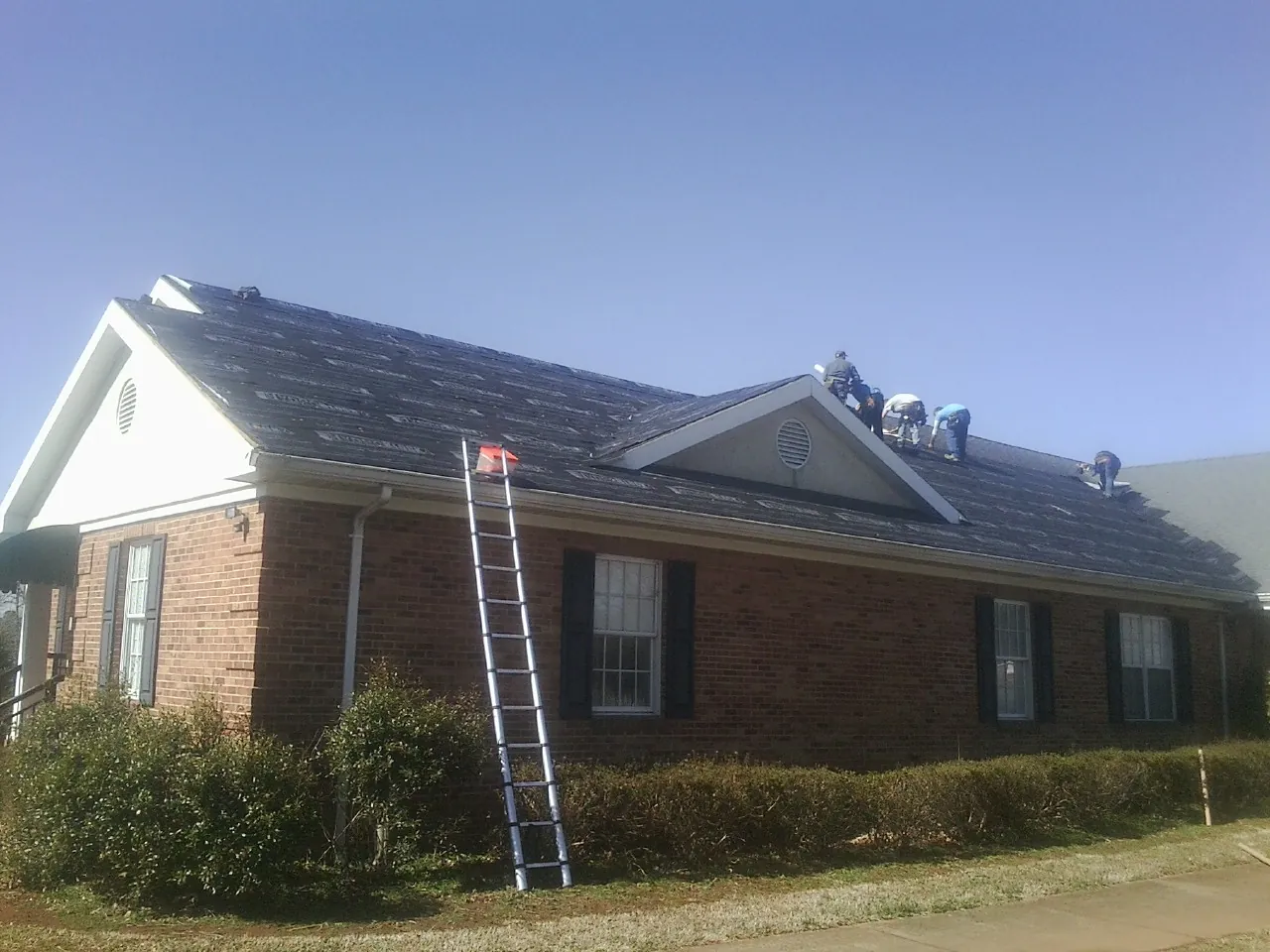 Crew tearing shingles off a brick ranch roof with a ladder set — Metal Roof Repair work by our crew in San Clemente